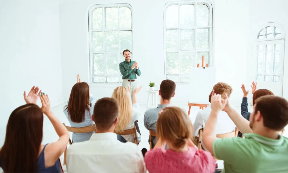 A group of people applauding a speaker at the front of the room