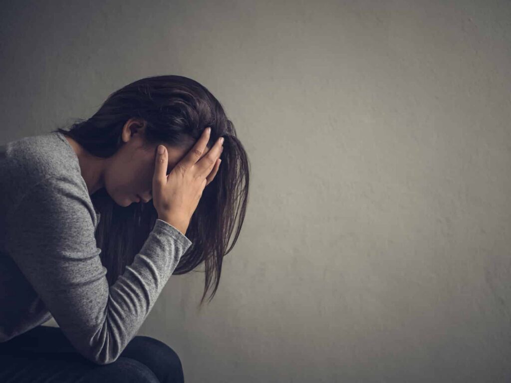 Woman with head in hands, expressing distress, symbolizing emotional struggles related to Xanax withdrawal and addiction recovery.