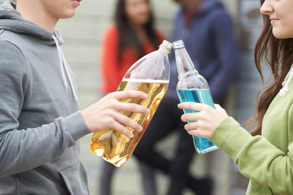 Individuals holding a bottle of Alcopops