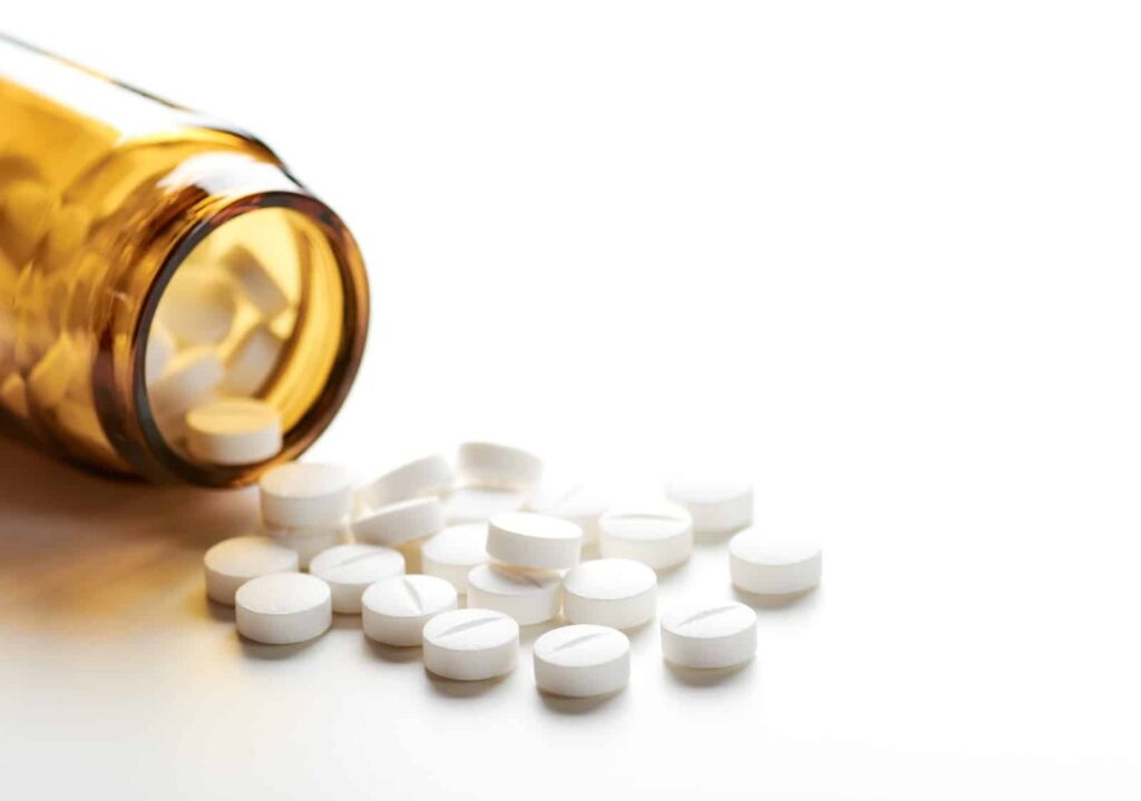 White Percocet® pills spilled from an amber prescription bottle, illustrating the medication's presence and potential risks in pain management and addiction discussions.