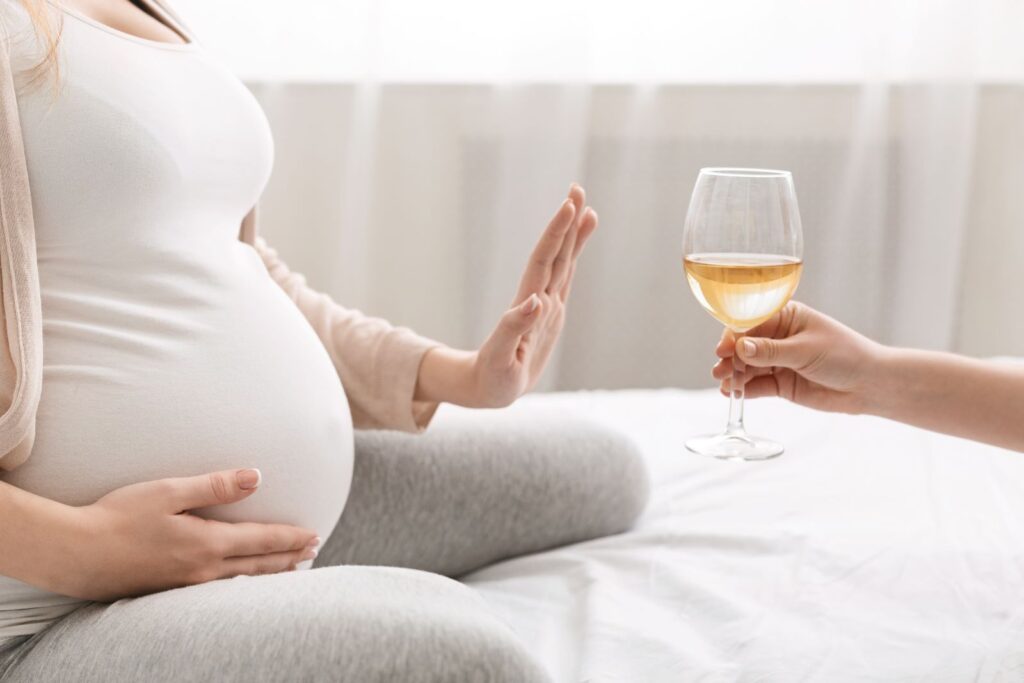 Pregnant woman rejecting a glass of wine, symbolizing the importance of abstaining from alcohol during pregnancy to prevent fetal alcohol syndrome.