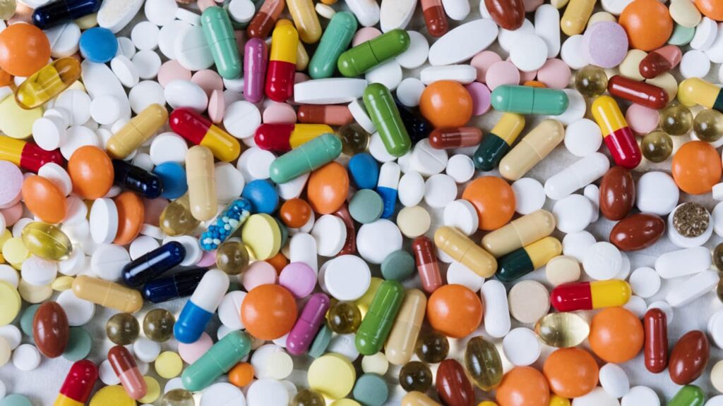 Assorted colorful pills and capsules representing various medications, including stimulants like Modafinil and Adderall, on a neutral background.