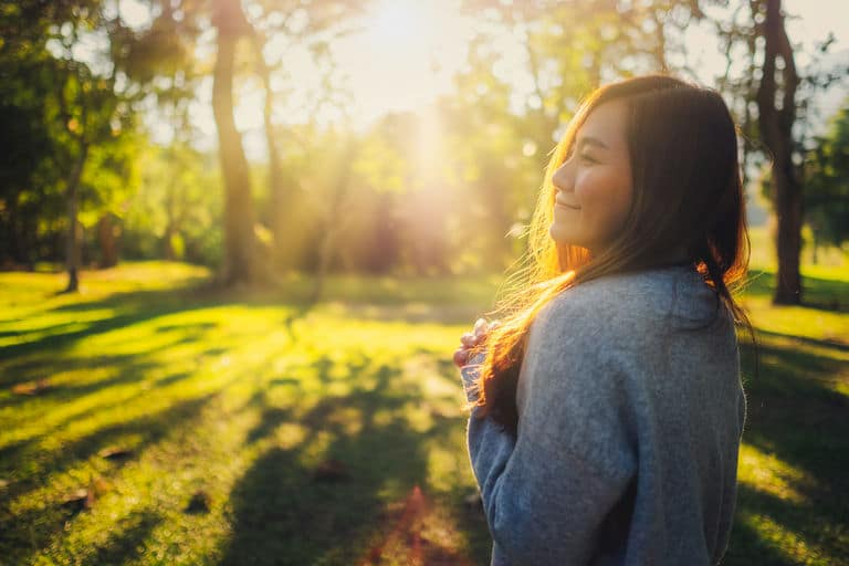 Young woman enjoying nature in a sunlit park, symbolizing serenity and outdoor sober activities in Los Angeles.