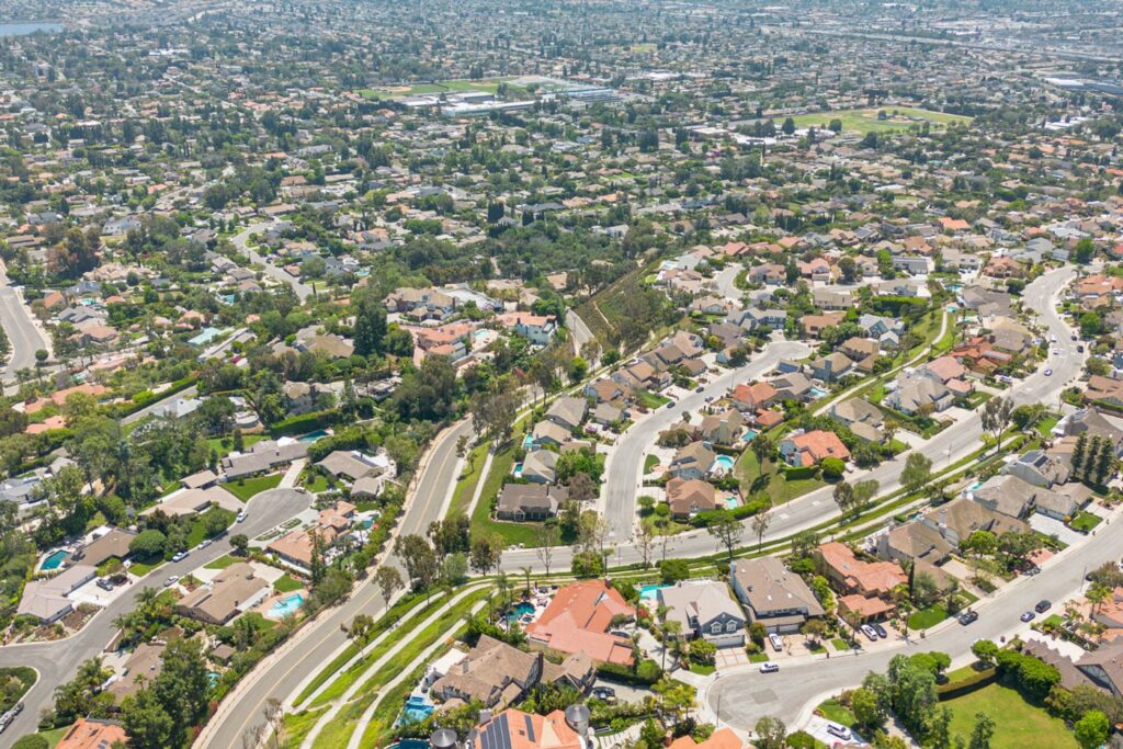 Aerial view of residential neighborhoods in Orange County, showcasing houses, winding roads, and green landscaping, relevant to local zero-proof drink options and community socializing.
