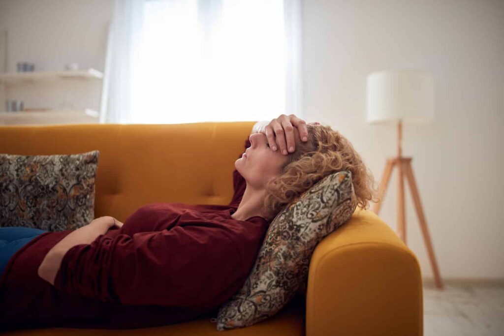 A woman lying on a sofa experiencing common side effects of fentanyl