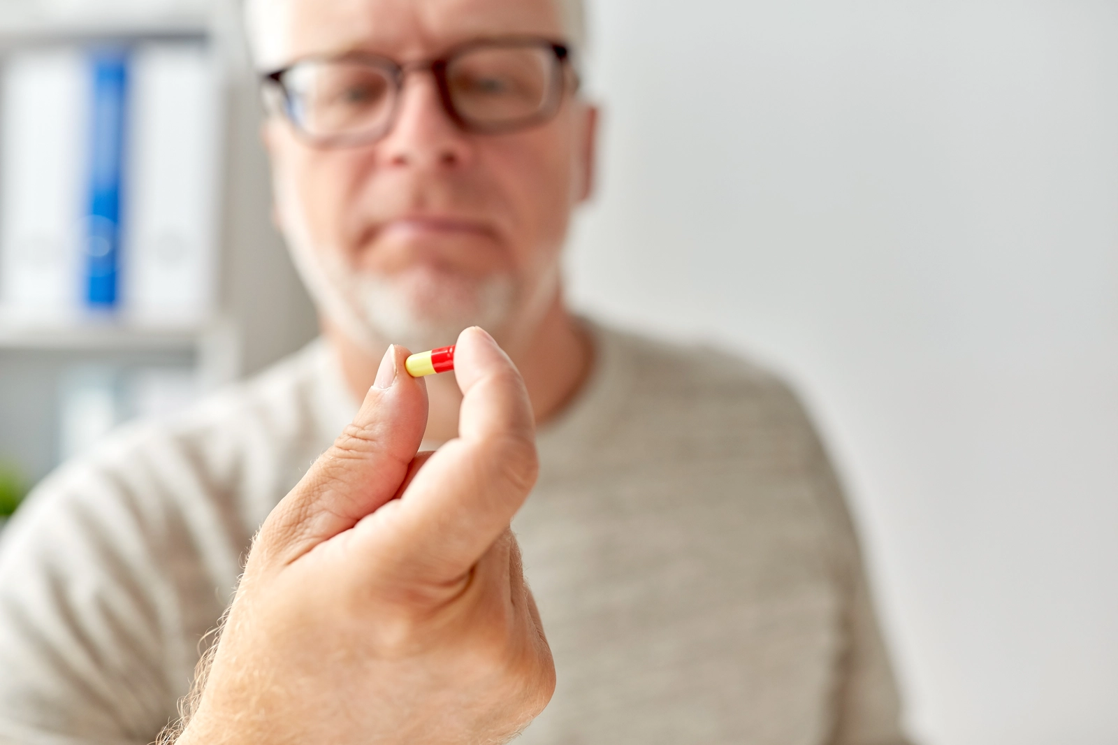 man holding up yellow and red pill
