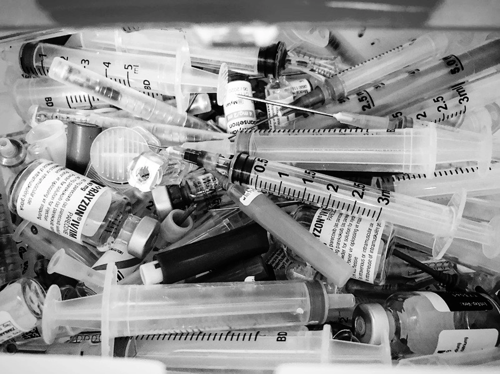 Black and white photo of syringes and pill bottles of addictive drugs