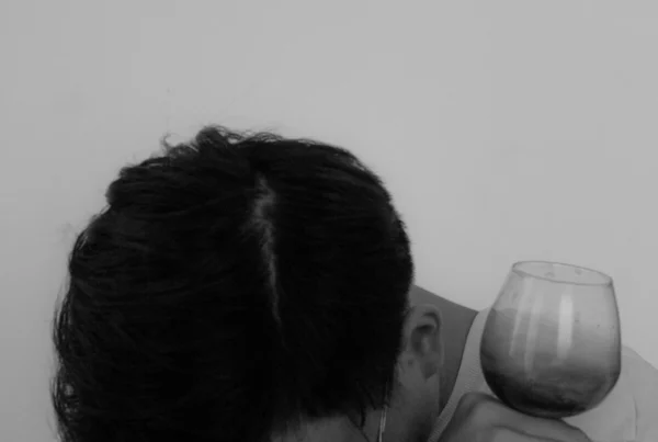 Man with wet brain syndrome with his head on his arm holding an empty wine glass