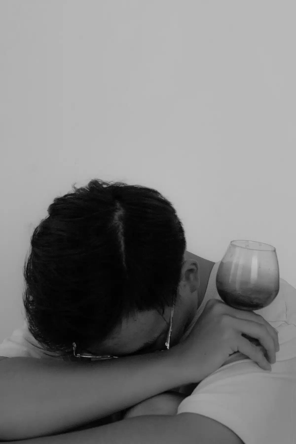 Man with wet brain syndrome with his head on his arm holding an empty wine glass