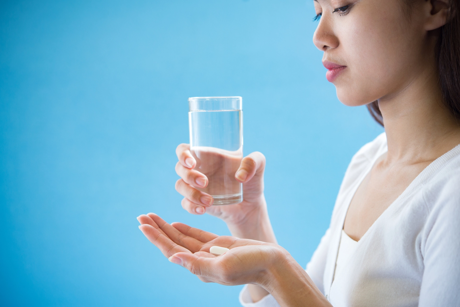 Woman holding a glass of water and anxiety medication pill in her hands