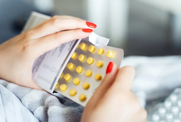Woman opening a box of anxiety medication and pulling out the blister packet of yellow pills