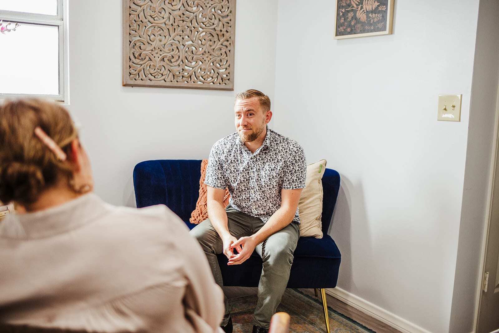 Person sitting on a blue couch in a therapy session, engaged in conversation about fentanyl addiction treatment.
