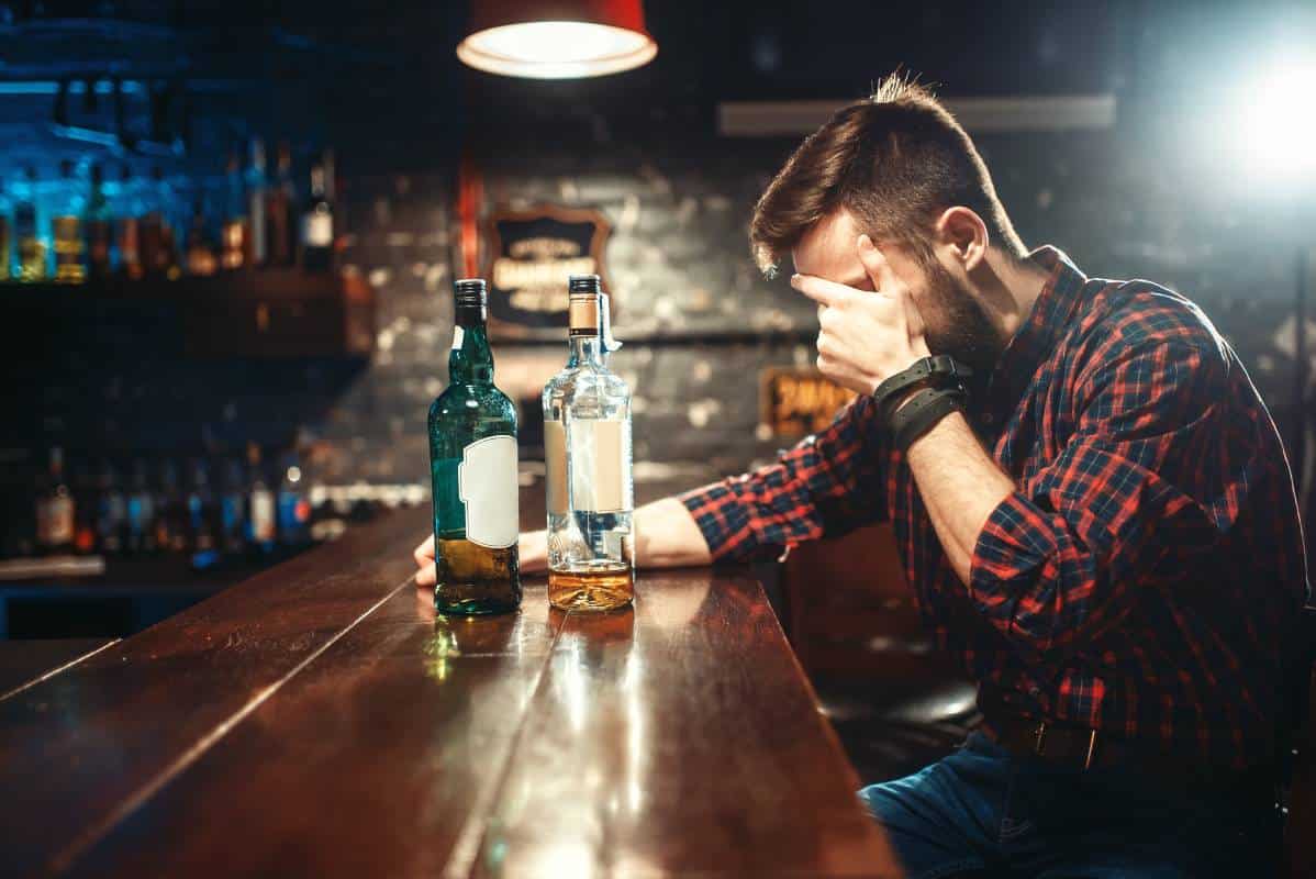Individual in a bar struggling with alcohol addiction