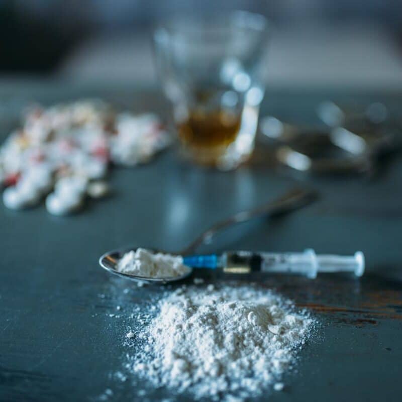 Image of powdered drug and a syringe on a table