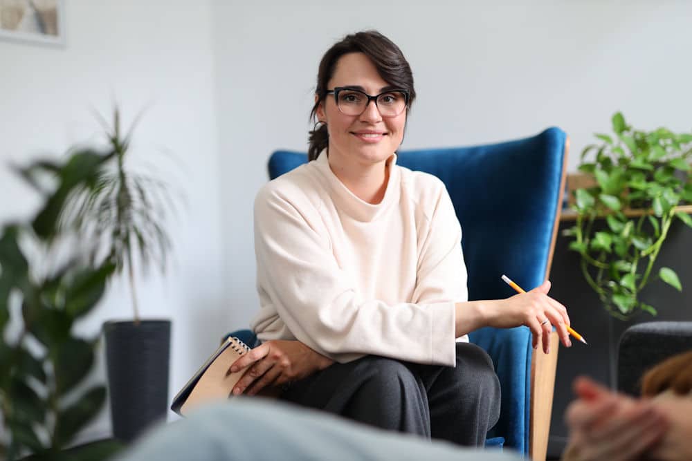 Therapist in blue chair offering support for benzodiazepine addiction recovery.